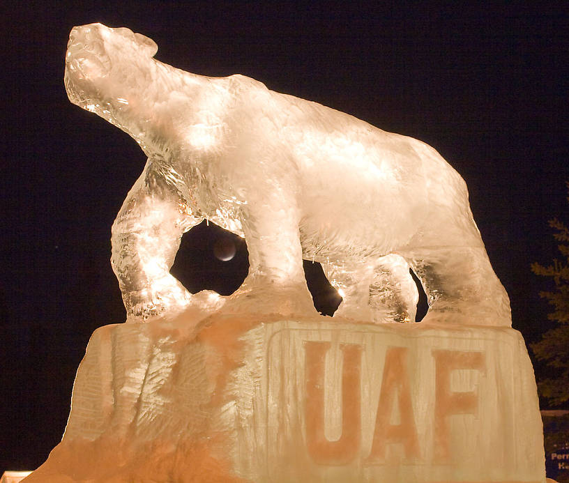 Polar bear ice sculpture with the eclipsed moon between its front legs.